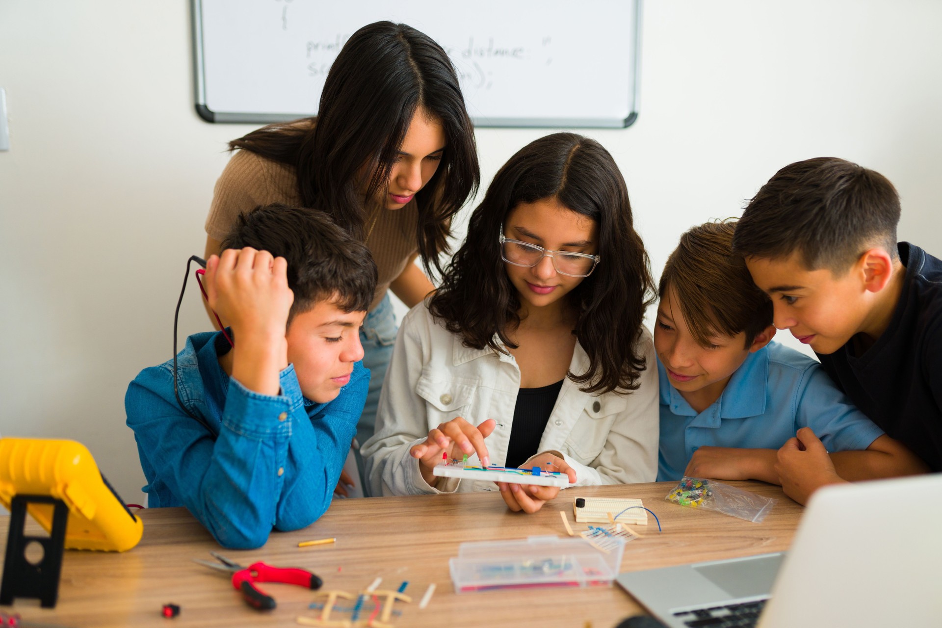 Happy smart teen boys and girls learning about electronics circuits