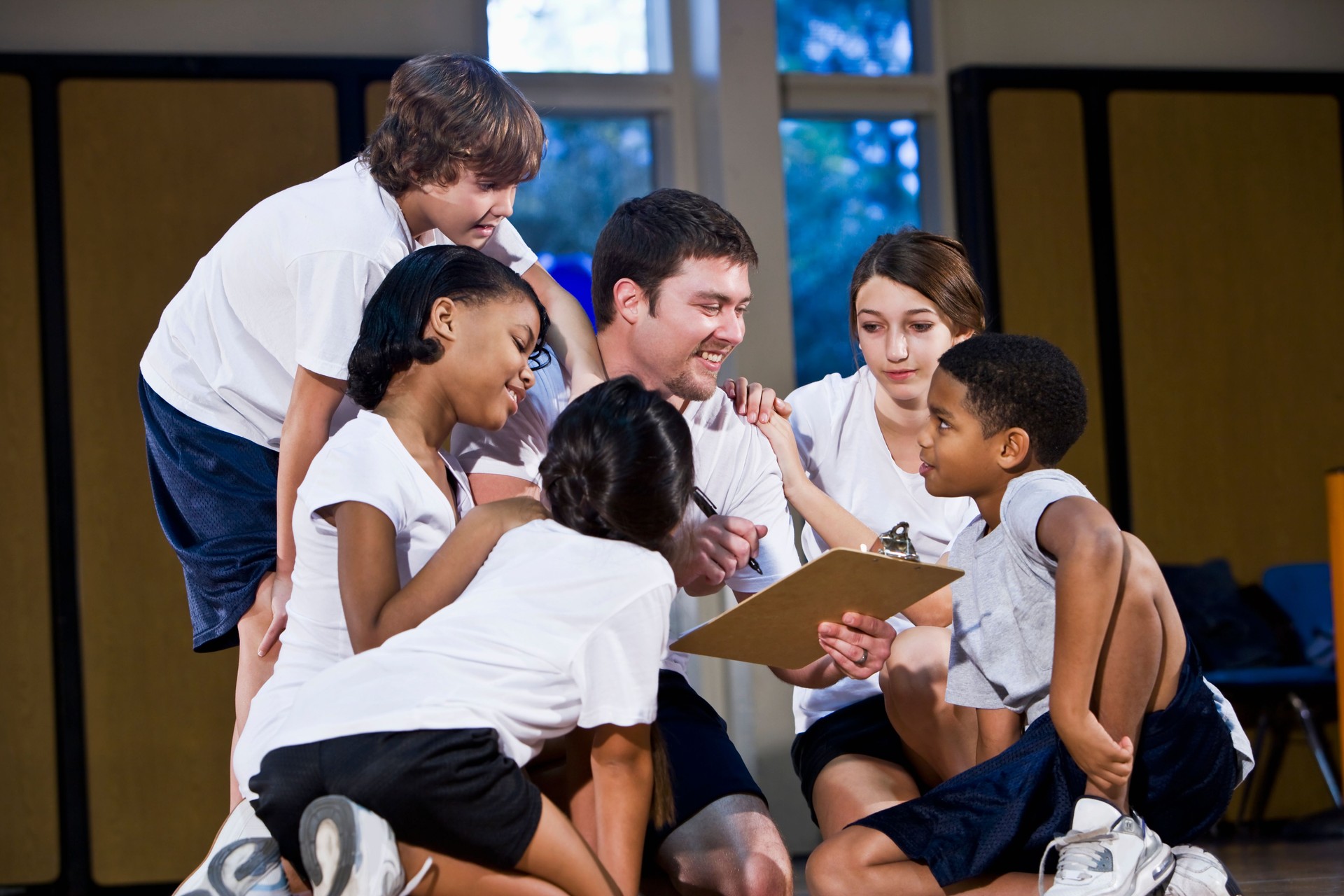 Diverse group of children in gym with coach