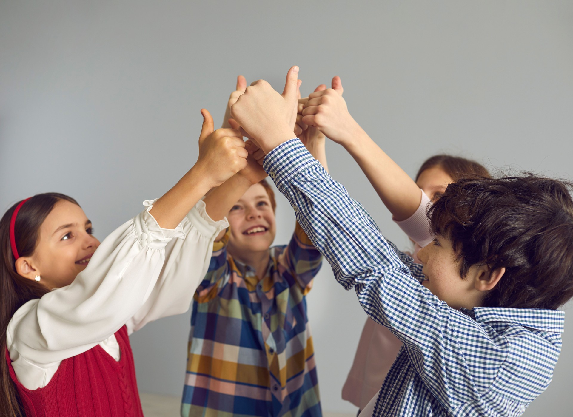 Group of positive little children give thumbs up as they join their hands together