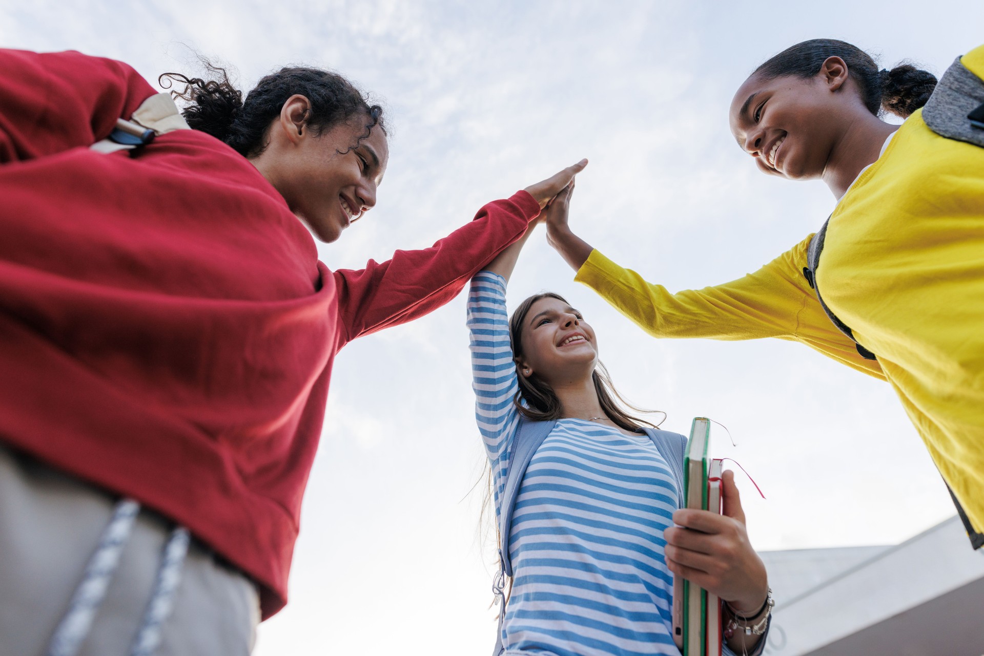 Group of teenagers celebrating with a high five outdoors