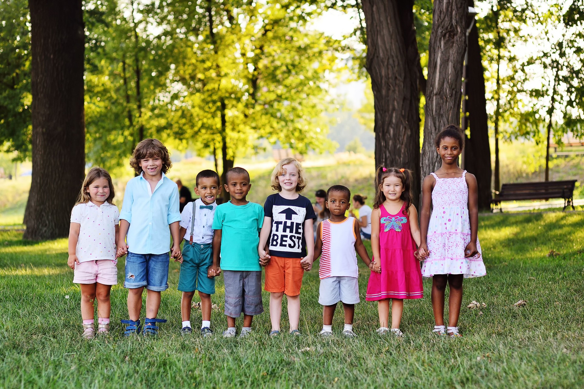 many young children of different races play together in the Park on the green fresh grass